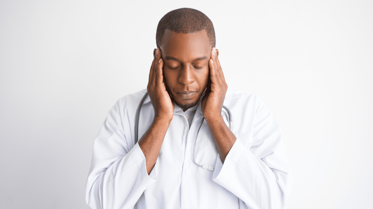 Blog content photo for Physician Physician Wellness in America Blog content photo for Physician Physician Wellness in America, depicting a physician holding his head possibly suffering from a headache due to the stress of the Covid-19 pandemic.